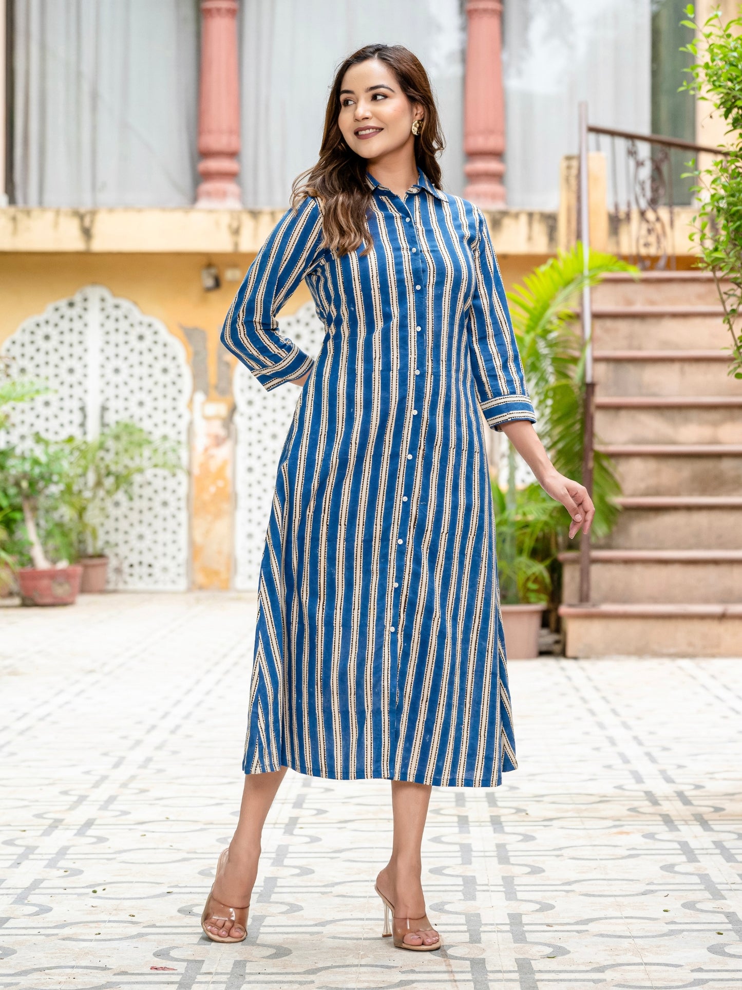 Woman wearing a blue and white striped dress standing outdoors.