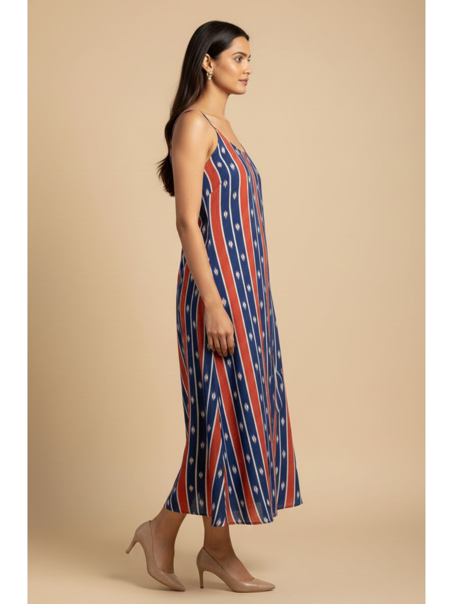 Model walking in handmade ikat cotton noodle strap dress with blue and red stripes, showcasing fluid movement and relaxed summer styling.